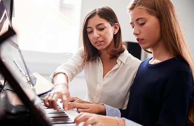 piano teacher and student
    	sitting at a piano